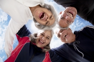 Gruppe von Senioren stehen im Kreis, umarmen sich und lachen